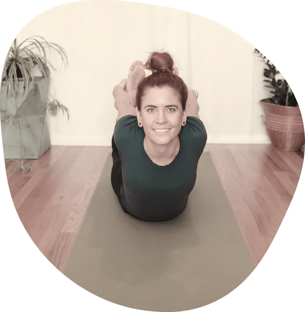 Yoga teacher practicing cobra pose on a mat in a bright studio space